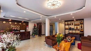 Vestíbulo de hotel con una recepción, un árbol de Navidad, una cafetería y una zona de estar.