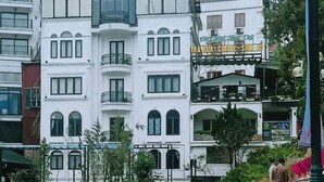 Un hotel con fachada blanca, balcones y un letrero que dice 'Melody Hotel & Restaurant'.