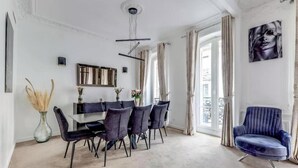 A dining area with a modern table and chairs, a vase with dried plants, and a large mirror on the wall. - AN AUTHENTIC PARISIAN ELEGANCE MOMENTS FROM ICONIC LANDMARKS – CHAMPS ELYSEES (Paris)