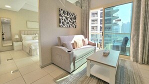 Une chambre d’hôtel moderne équipée d’un lit, d’un canapé, d’une table à manger et d’une grande fenêtre donnant sur la ville.