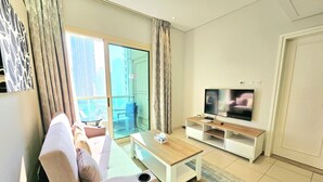 Un salon moderne avec un canapé, une table basse, un téléviseur et un balcon doté d’une porte vitrée.