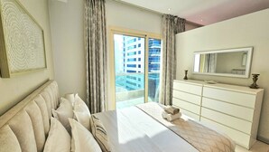 Une chambre d’hôtel avec un grand lit, une commode, un miroir et une vue sur un immeuble par la fenêtre.