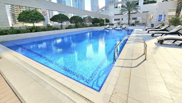 Une piscine avec des chaises longues et, en arrière-plan, une vue sur de hauts immeubles.