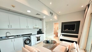 Un apartamento moderno con kitchenette, un sofá, una televisión y un comedor.