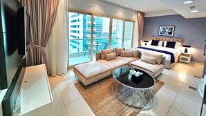 Un salón moderno con un conjunto de sofás, una mesa de centro y una cama con vistas a la ciudad.