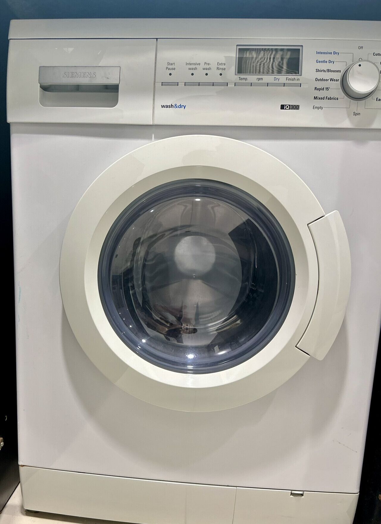 Vista frontal de uma máquina de lavar branca Siemens, com visor digital e painel de comandos.