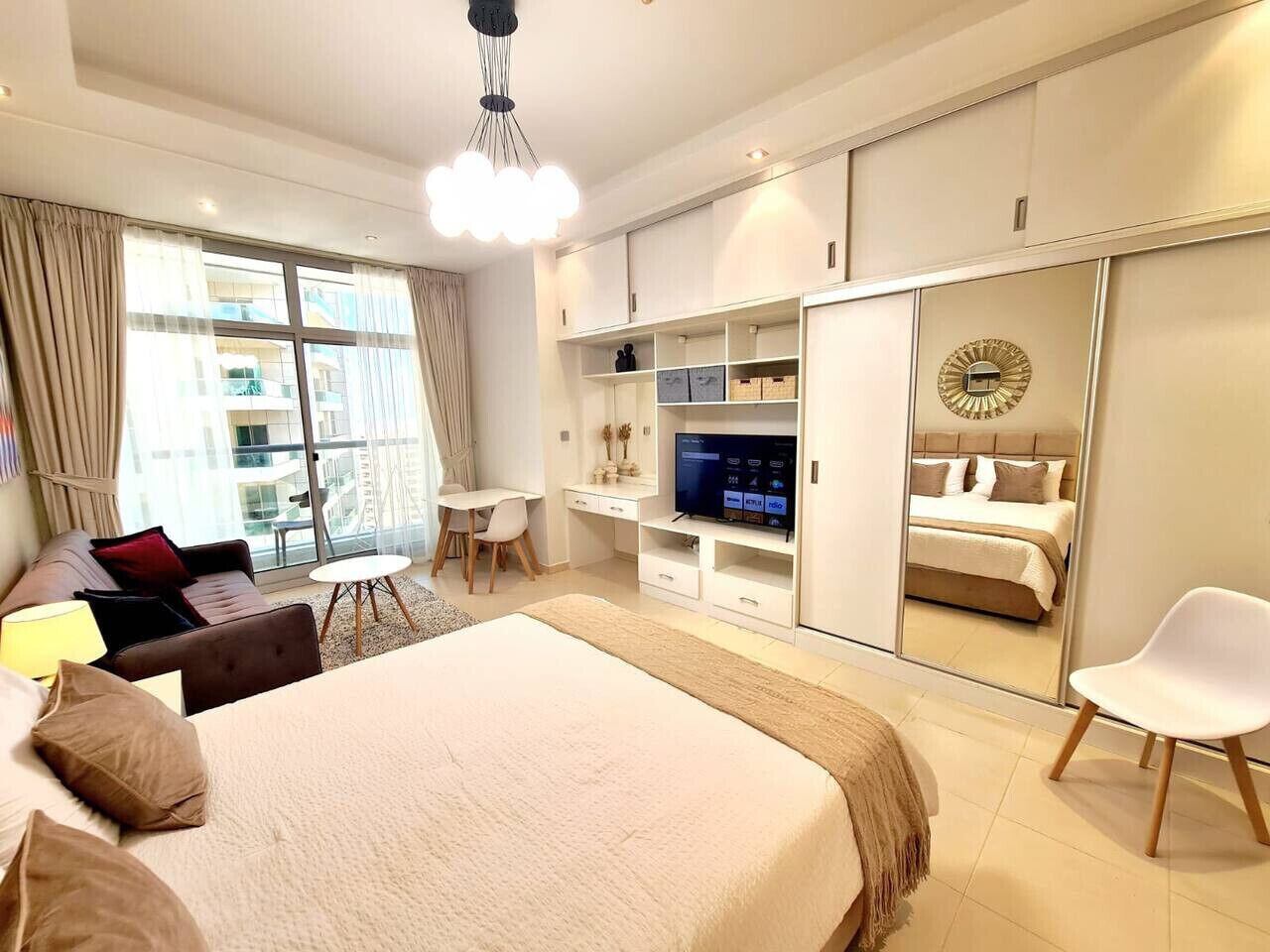 A modern hotel room with a large bed, a desk, a TV, and a wardrobe.