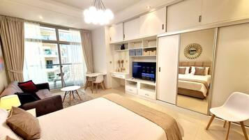 A modern hotel room with a large bed, a desk, a TV, and a wardrobe.