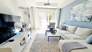 Una sala de estar moderna con un televisor de pantalla plana, un sofá, una mesa de centro y un tapete estampado.