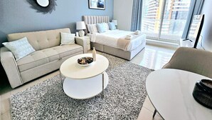 A modern living room with a sofa, a round coffee table, and a bed.