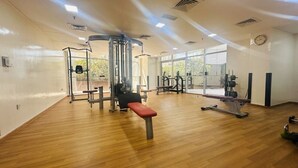 Una palestra con pavimenti in legno, attrezzature da allenamento e ampie finestre.