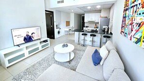 Un salon moderne comprenant un téléviseur, un canapé, une table basse et un coin cuisine.