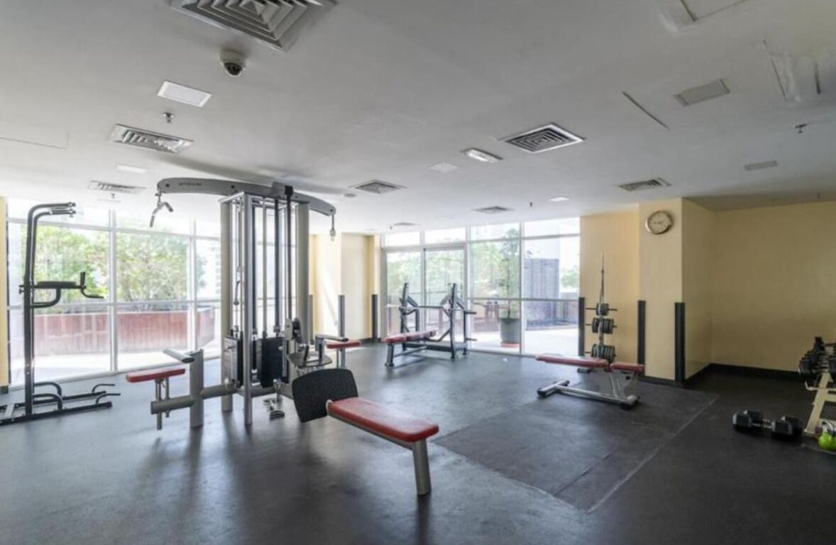 A gym with various exercise equipment, large windows, and a clock on the wall.