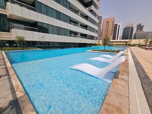 A swimming pool with a tiled deck and a modern building in the background.