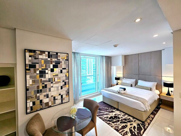 Ein modernes Hotelzimmer mit einem großen Bett, einem Schreibtisch mit Stuhl, einer Wanddekoration und einem großen Fenster mit Blick auf die Stadt.