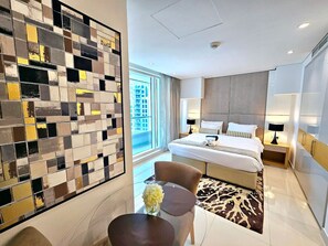 Ein modernes Hotelzimmer mit einem großen Bett, einer Sitzecke mit Tisch und Stühlen sowie einer Wand mit einem Mosaikmuster.