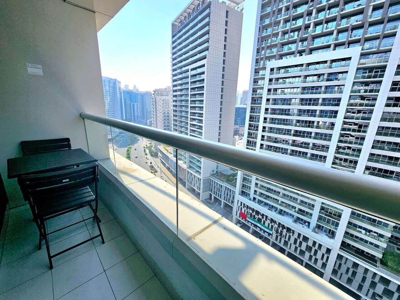 A balcony with a metal railing, a black table, and a black chair.