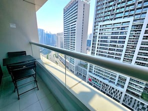 A balcony with a metal railing, a black table, and a black chair. - Sunrise Homes - Chic Studio close to Dubai Mall with Canal Views (Business Bay)