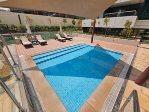 A swimming pool with lounge chairs and a covered area.