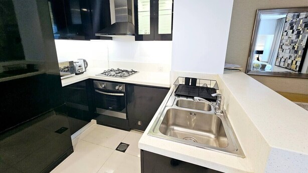 A modern kitchen with black cabinets, a stainless steel sink, and a gas stove.
