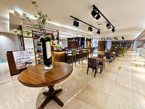 Ein modernes Restaurant mit glänzendem Marmorboden, Holztischen und verschiedenen Sitzgelegenheiten.