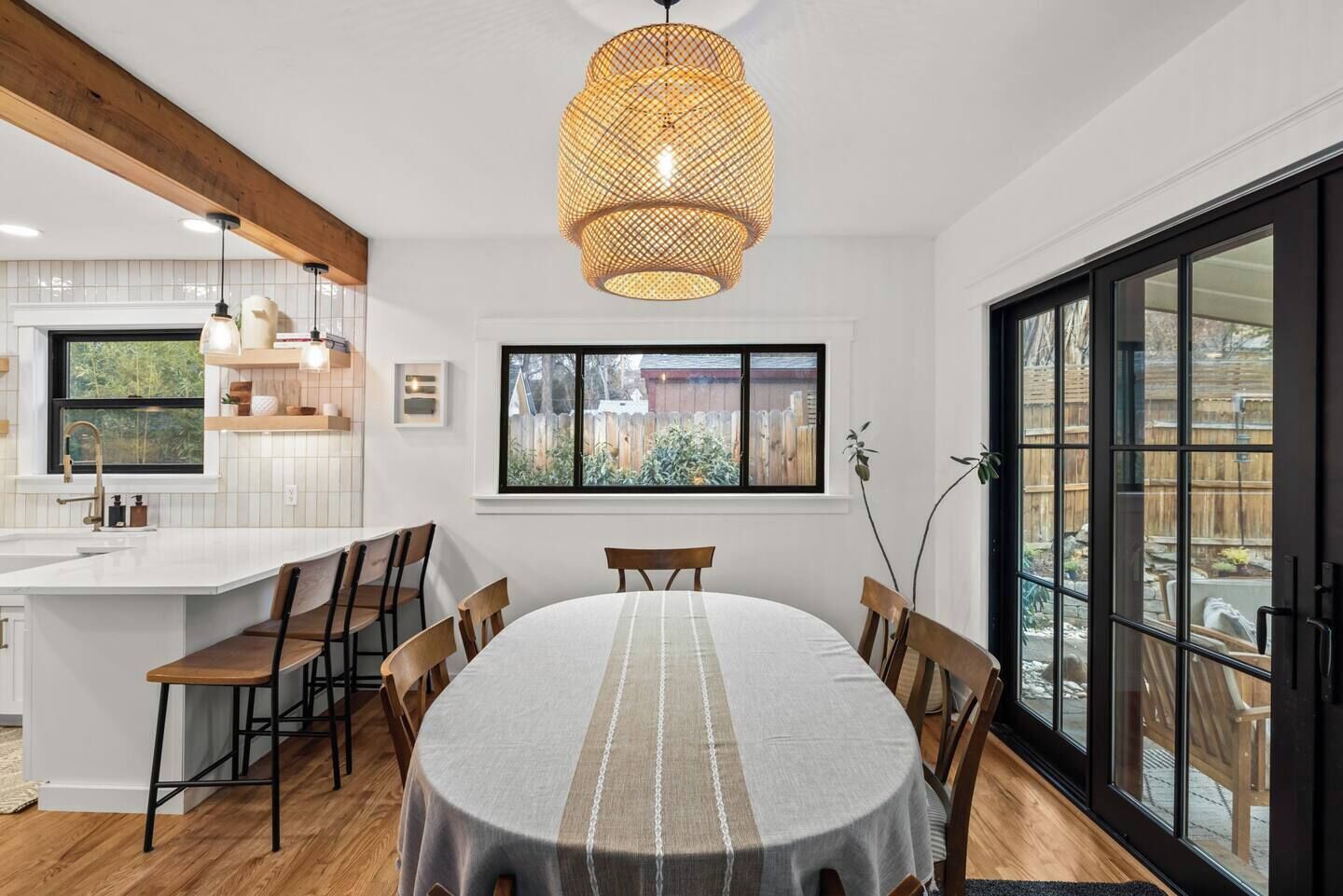 Una cucina moderna con una grande isola, sedie in legno e un tavolo da pranzo con tovaglia a righe.