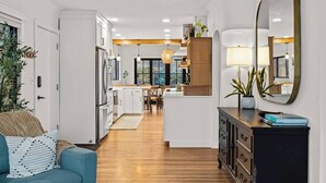 Una cocina moderna con armarios blancos, una isla de madera e iluminación colgante.