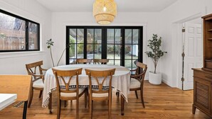 Un comedor con una mesa redonda, sillas de madera y una lámpara colgante.