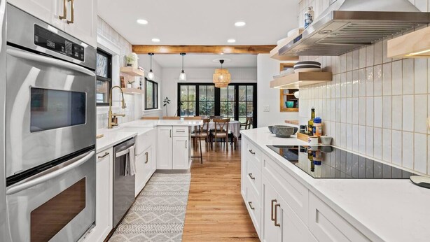Una cocina moderna con armarios blancos, electrodomésticos de acero inoxidable y suelo de madera.
