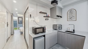 Een moderne keuken met een inbouwmagnetron, broodrooster en spoelbak. Er is een kleine koelkast en een raam met uitzicht op de omgeving.