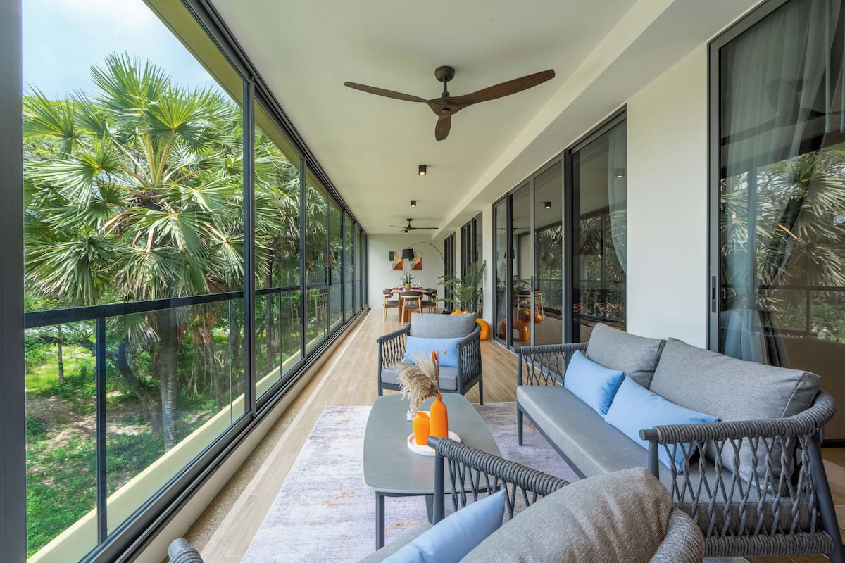 A spacious balcony with a sofa, chairs, and a table.