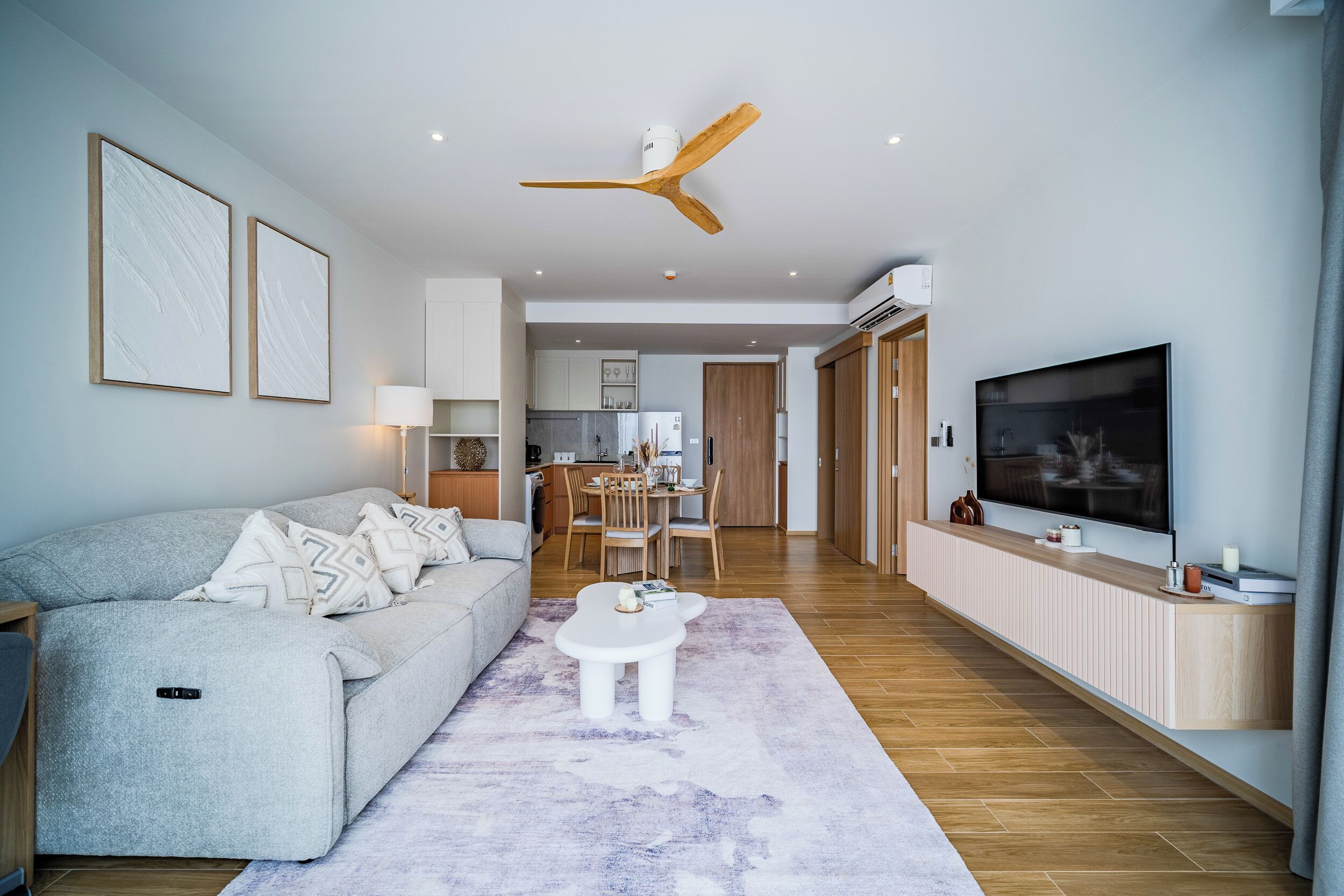 A modern living room with a sofa, coffee table, TV, and ceiling fan.