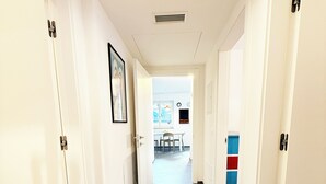 A hallway with white doors, a framed picture on the left wall, and a view into a room with a table and chairs. - Apartment in the center of Levico with 3 bedrooms, 2 bathrooms, terrace,garage and elevator (Levico Terme)