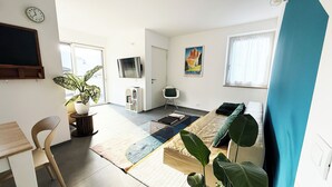A modern, well-lit room with a bed, a desk, a chair, a TV, and a large window. - Apartment in the center of Levico with 3 bedrooms, 2 bathrooms, terrace,garage and elevator (Levico Terme)