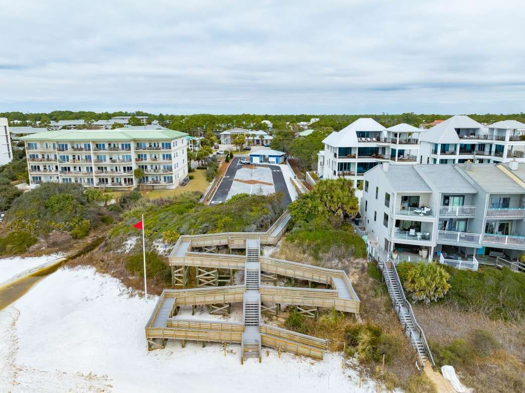A beachfront hotel with multiple balconies, a boardwalk, and a sandy beach.