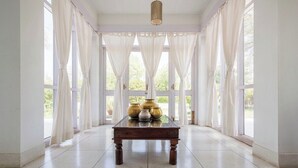 Une pièce avec une table en bois, des rideaux blancs et de grandes fenêtres.