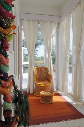 Um quarto com uma cadeira de vime, uma cesta trançada e uma pena de pavão como decoração.