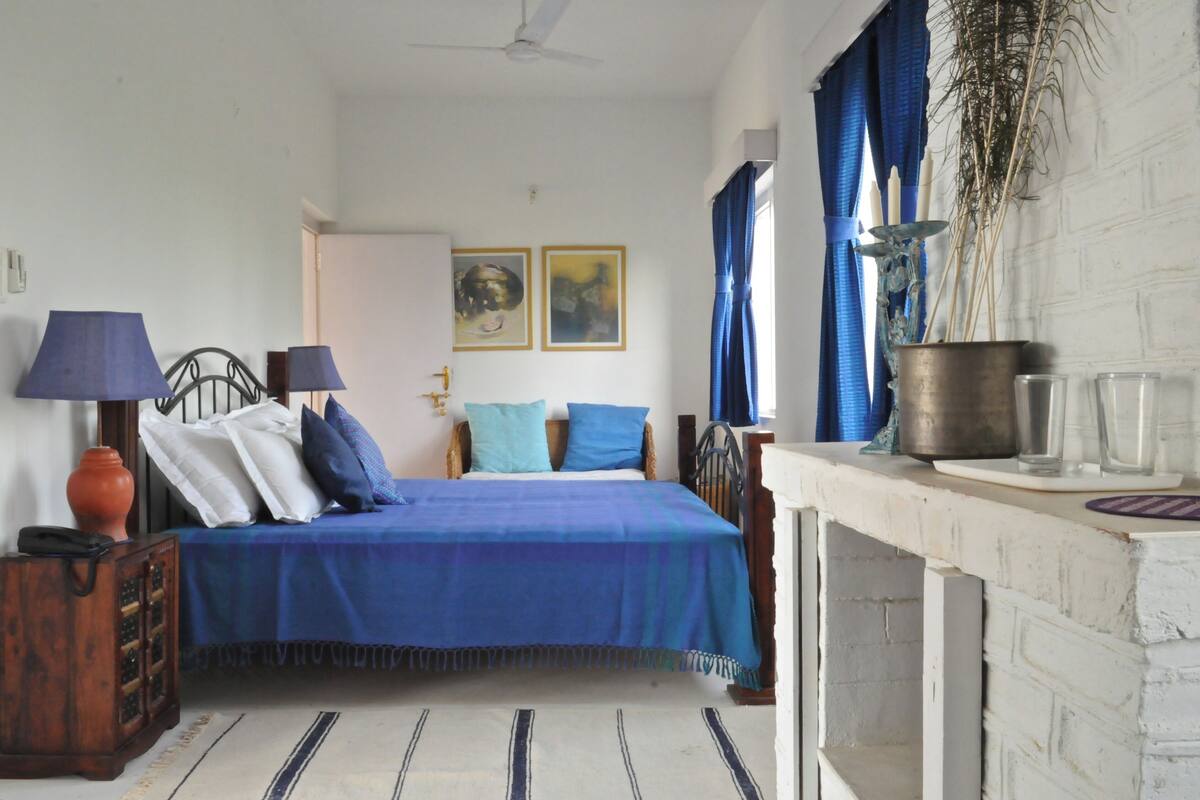 Une chambre à coucher avec un lit, deux lampes, un vase et une fenêtre avec des rideaux.