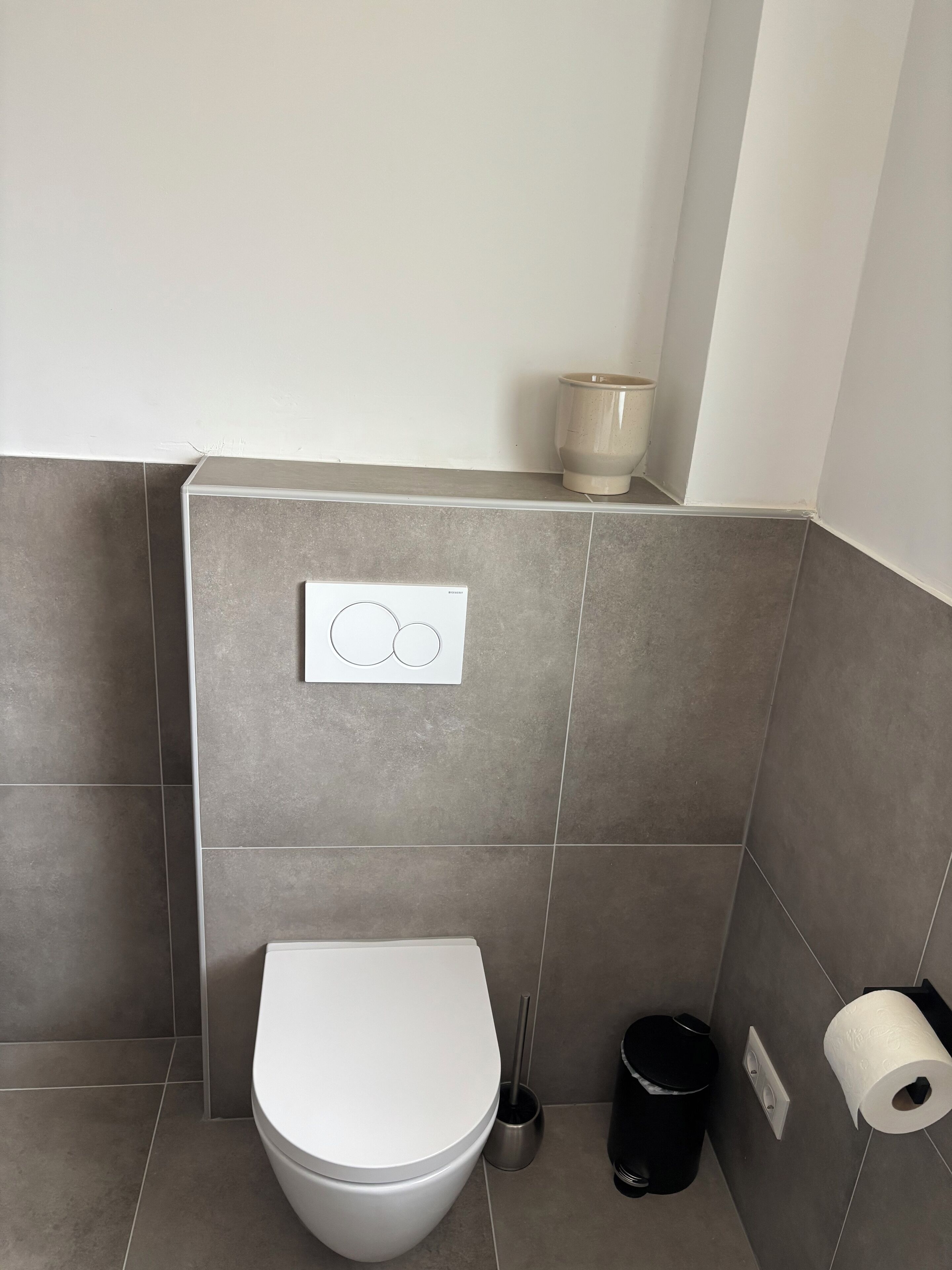 Ein modernes Badezimmer mit Toilette, Bidet, Toilettenpapierhalter und Mülleimer.