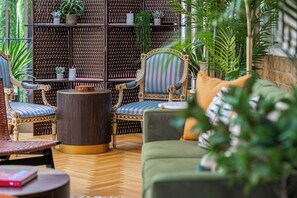 A cozy indoor seating area with wicker furniture, a round wooden table, and a green sofa. - Luxury flats near Big Ben and London Eye (London)