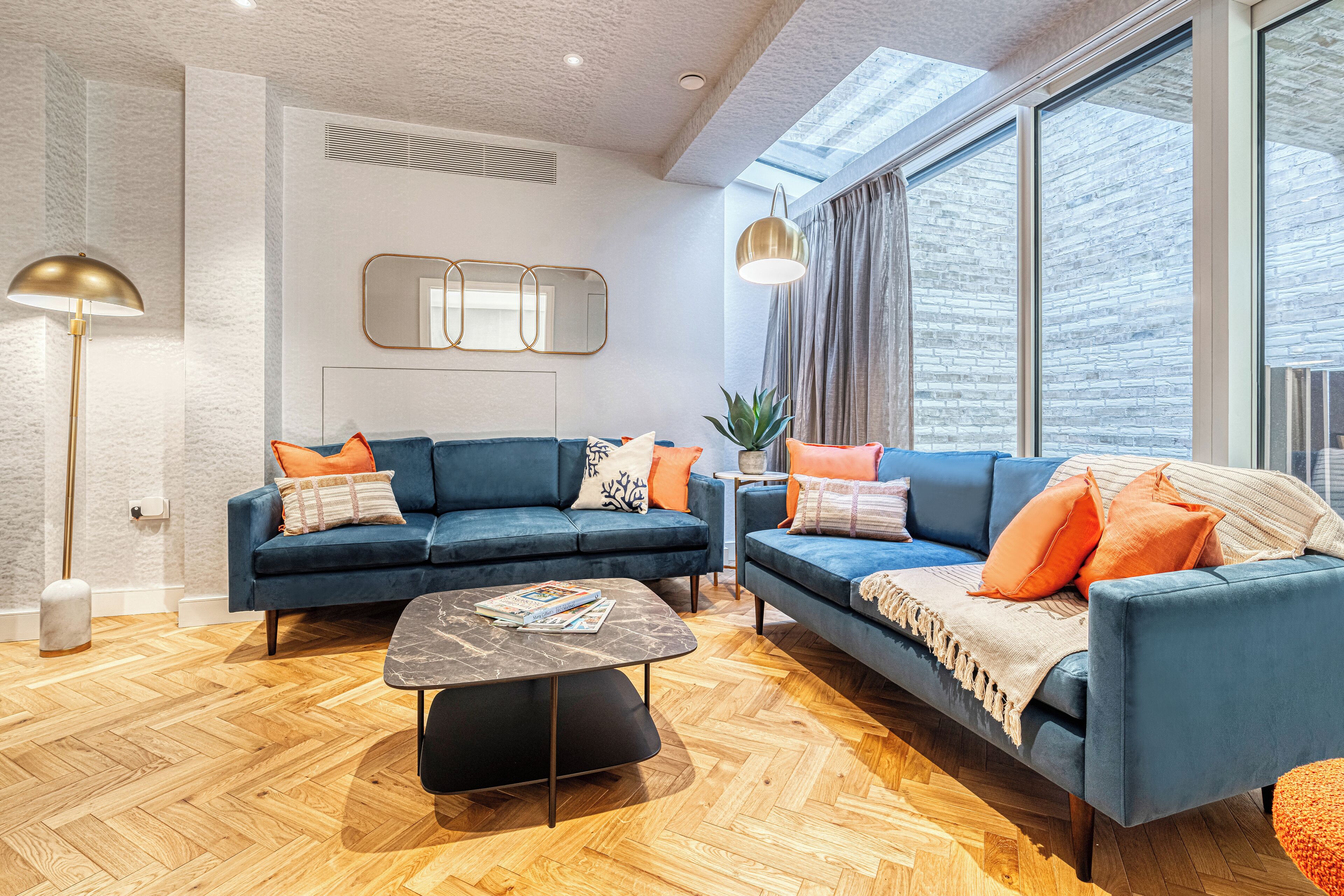 Un salon moderne avec deux canapés bleus, une table basse et un lampadaire.