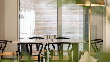 A dining area with a brick wall, a glass table, and chairs with woven seats.