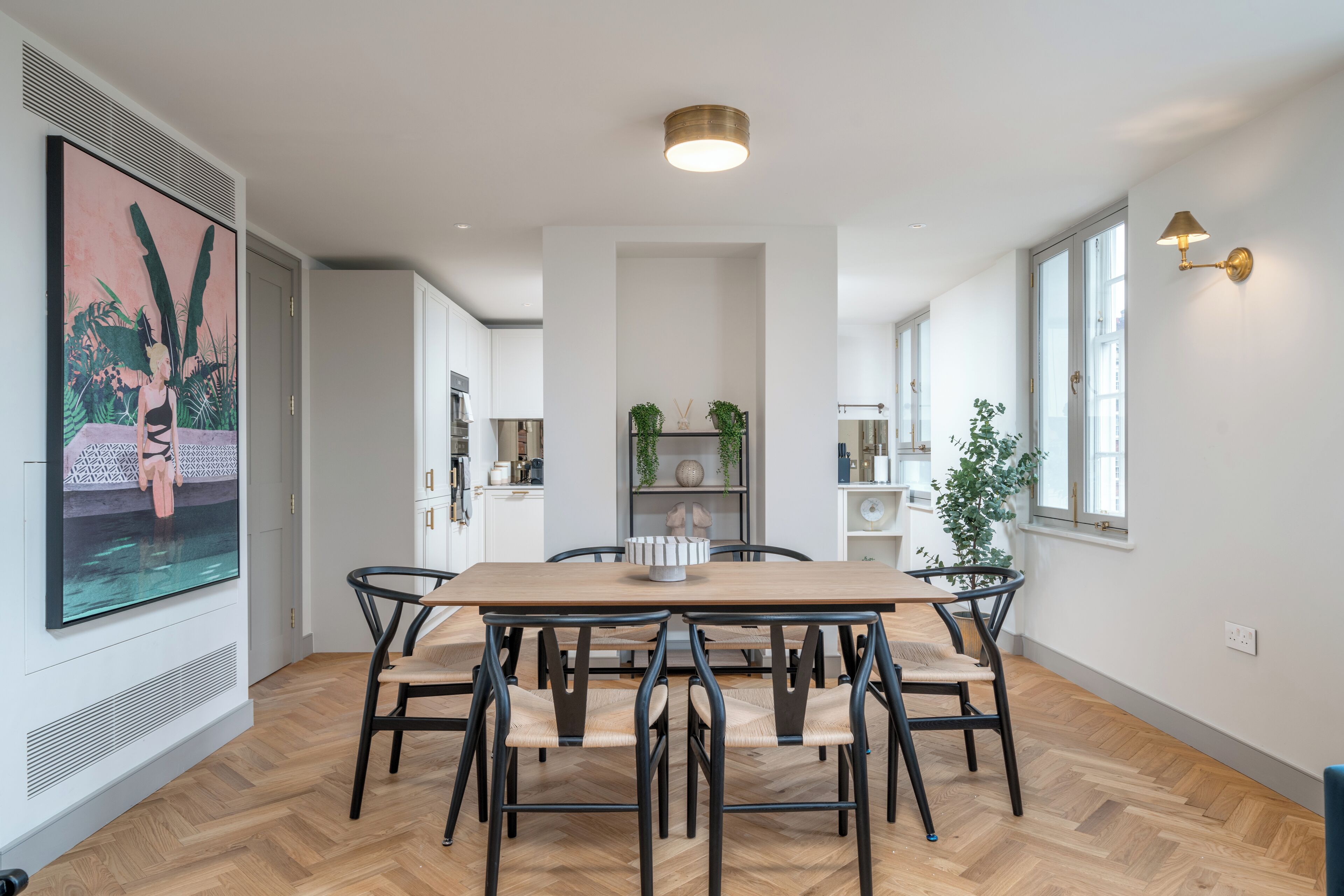 Un coin repas avec une table et des chaises en bois, un grand tableau au mur et un luminaire au plafond.