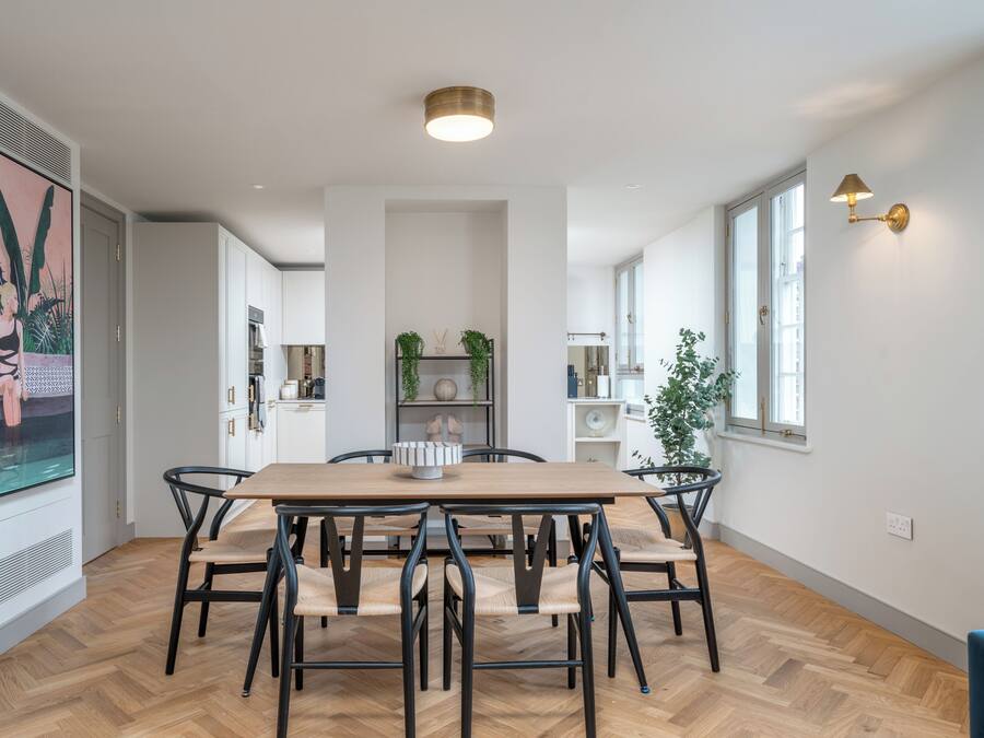 Un coin repas avec une table et des chaises en bois, un grand tableau au mur et un luminaire au plafond.