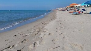 A beach with footprints leading to the water, umbrellas, and beach chairs. - Sirene452 - where to combine the relaxation of the sea and the proximity to the eternal city (Torvaianica)