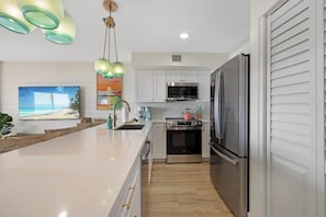 A modern kitchen with white cabinets, stainless steel appliances, and a large island with a sink.
