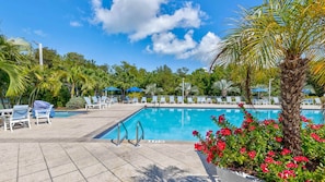 A pool area with lounge chairs, a swimming pool, and surrounding greenery.