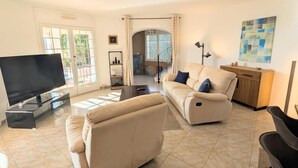 Ein geräumiges Wohnzimmer mit Flachbildfernseher, einem beigefarbenen Sofa und einem Couchtisch.