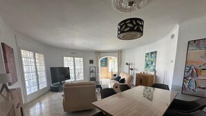 Ein geräumiger Wohnbereich mit Esstisch, Sofas und einem Fernseher.