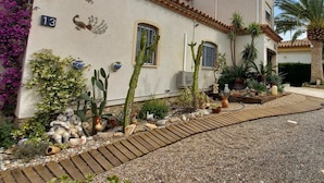 Ein Gebäude mit Ziegeldach, Hausnummer 13, und einem Garten mit Kakteen und Zierteichen.